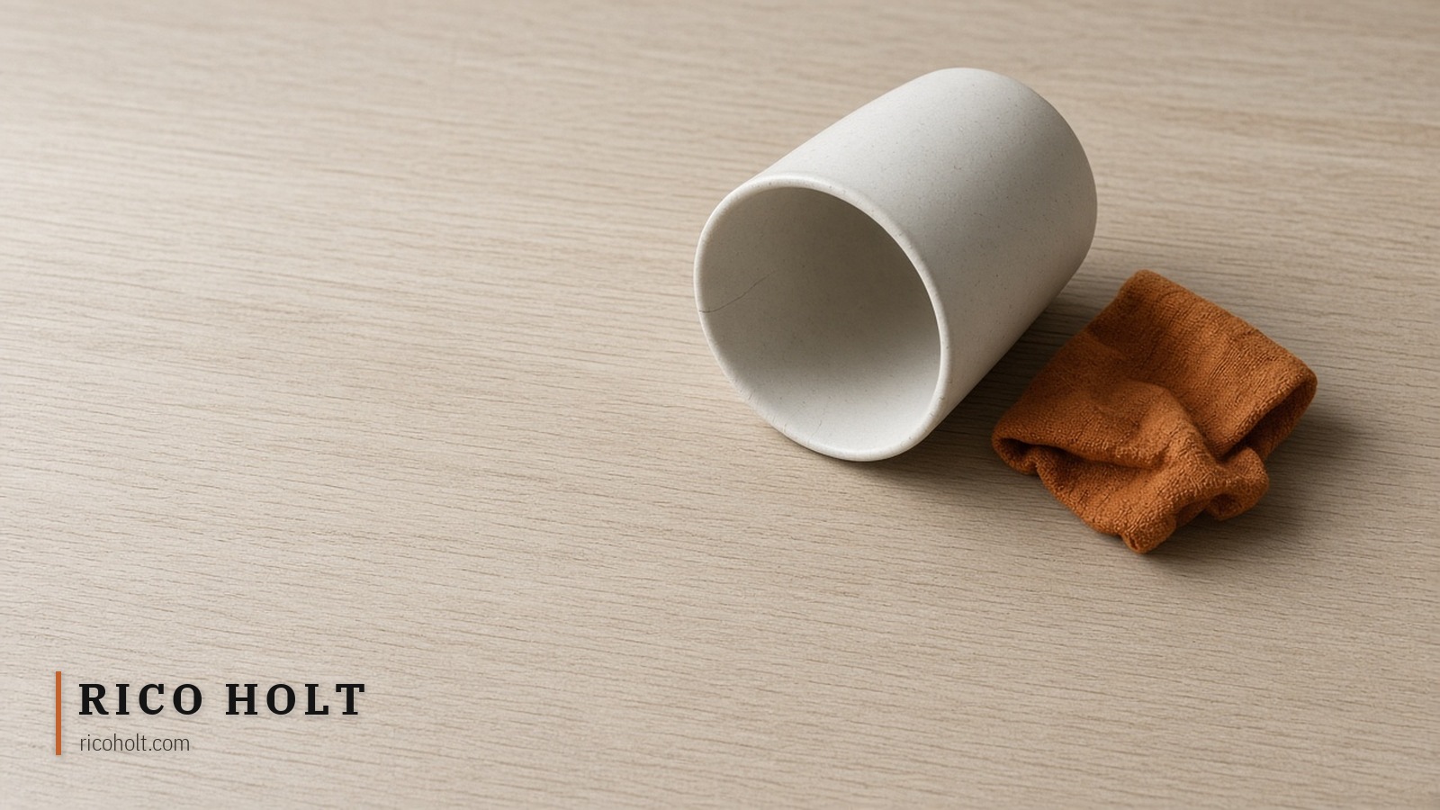 Empty pale desk with one toppled ceramic cup and a single ochre cloth scrap