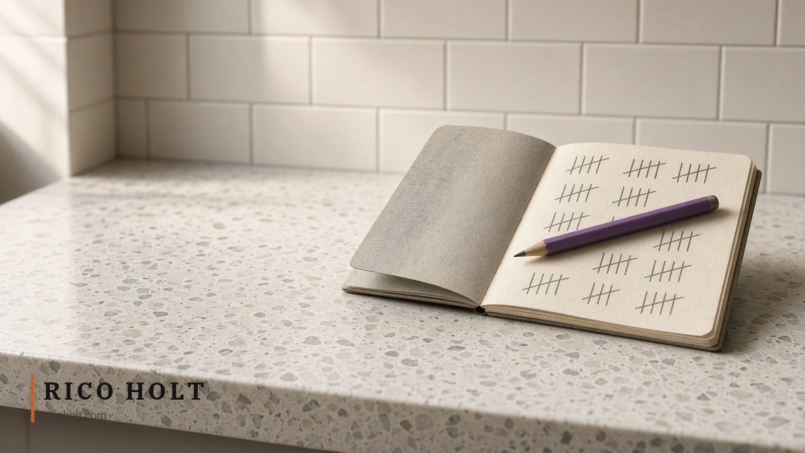 An open notebook of pencil tally marks with a purple pencil resting on it, on a speckled terrazzo counter against white tiles
