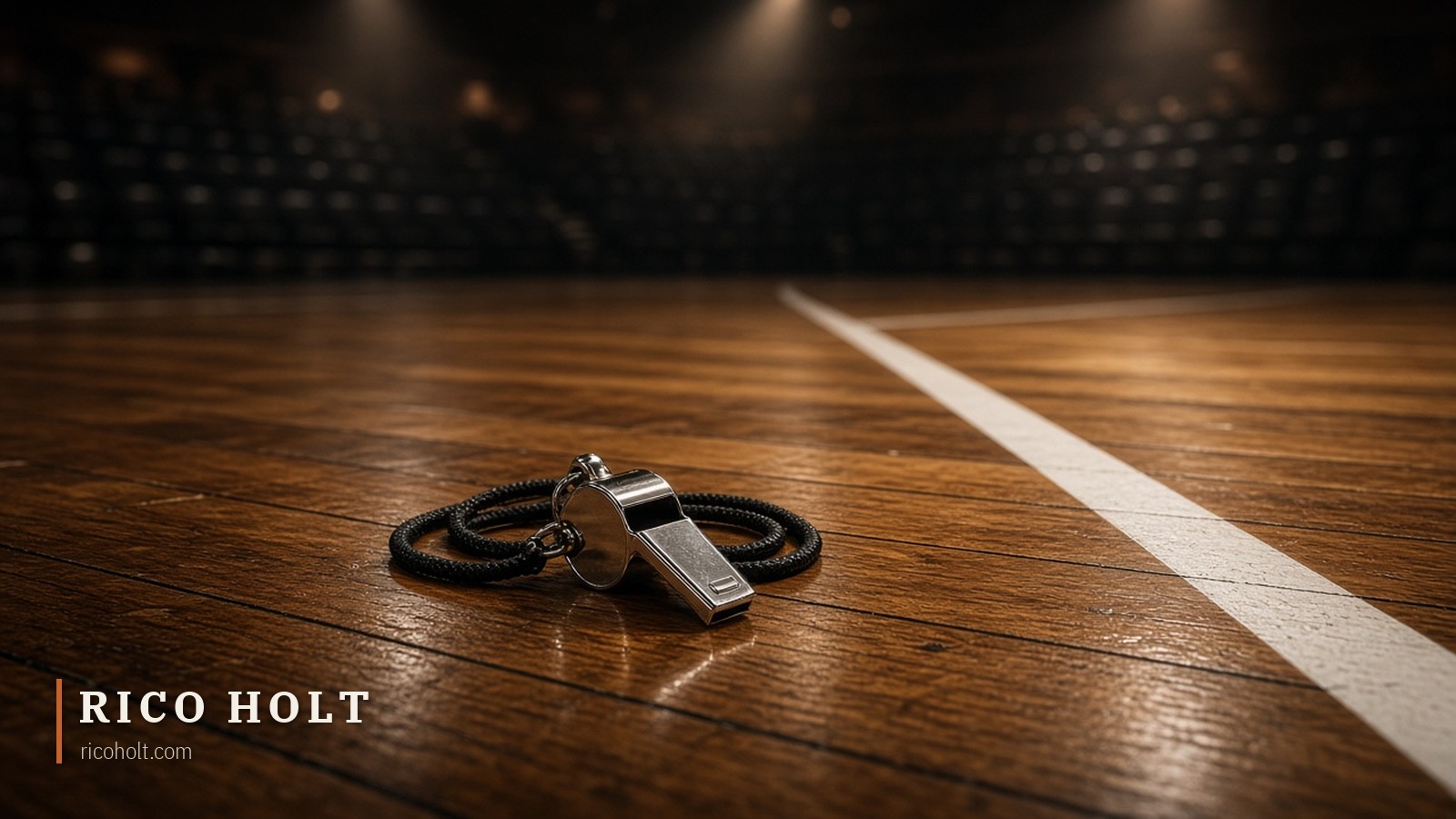 A metal whistle on a black cord lying on a polished basketball court