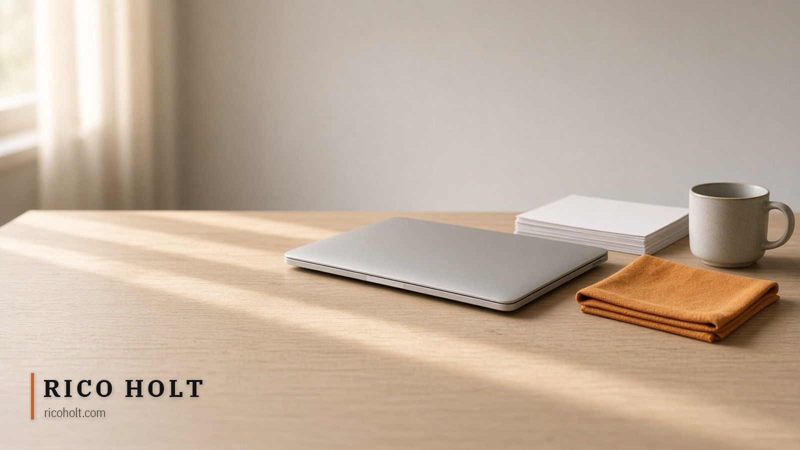 Empty pale desk with closed laptop, blank paper stack, mug, and one ochre cloth